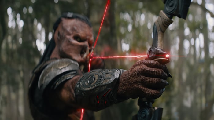 Predator aiming a bow with red laser sight