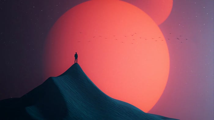 Silhouette of a person on a mountain under two large moons