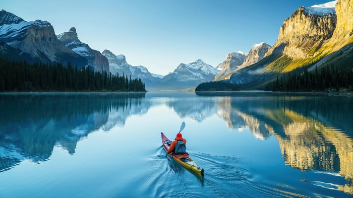 Kayaker on a calm lake with snow-capped mountains