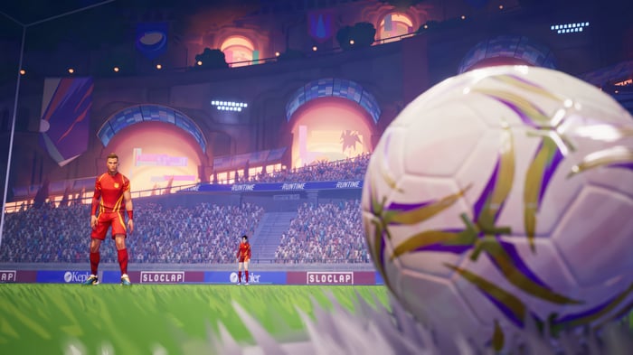 Soccer players in a stadium with a soccer ball in the foreground