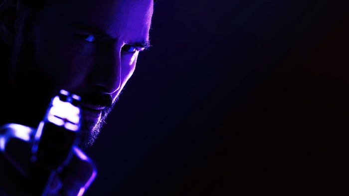 John Wick holding a gun in purple light 4K