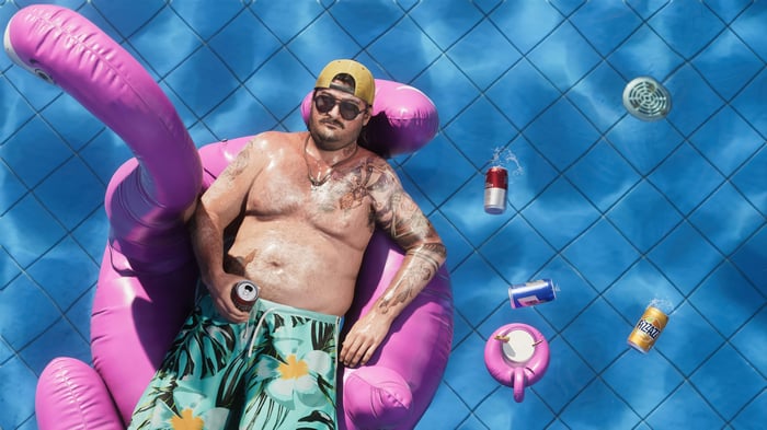 Man relaxing on a flamingo float in a pool with drinks