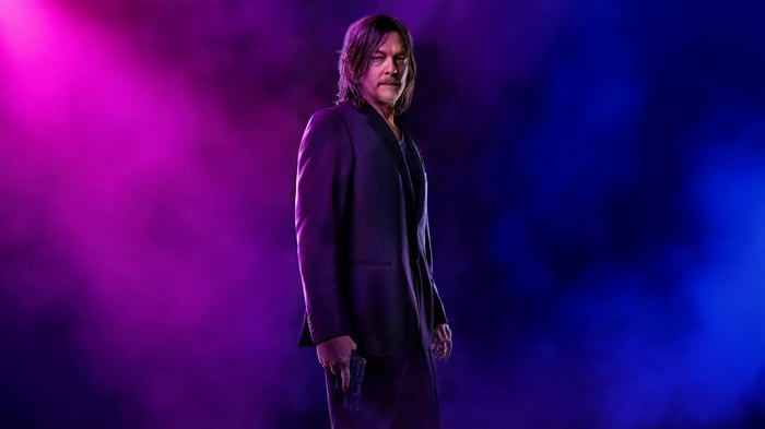 Norman Reedus in a suit holding a gun