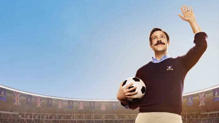 Ted Lasso holding a soccer ball in a stadium