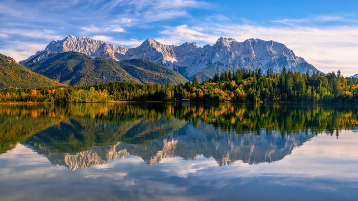Mountain range reflected in a lake with autumn forest