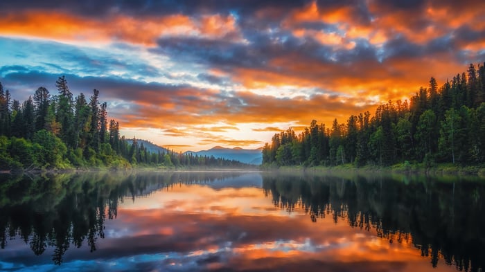 Sunset over a forest river with reflections
