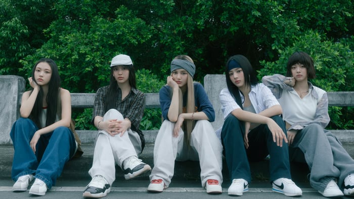 NewJeans members sitting on a ledge