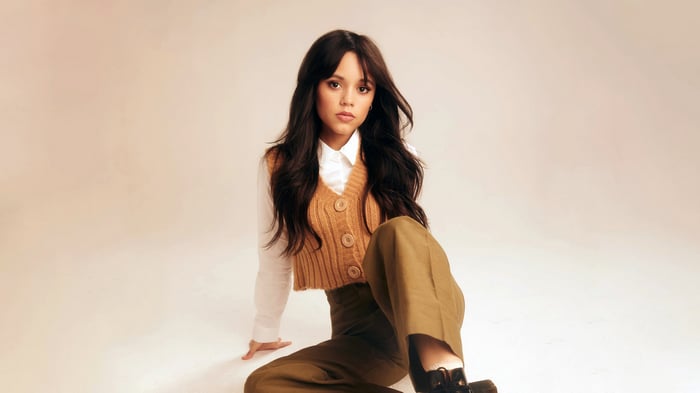 Jenna Ortega in a brown vest and green pants