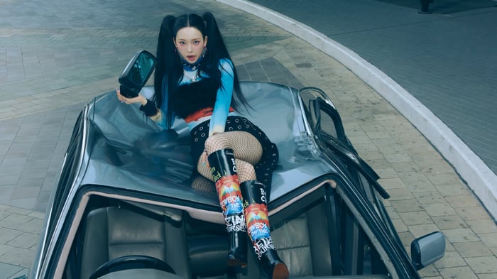 Karina from Aespa sitting on a car