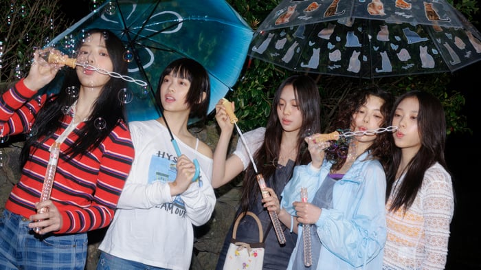 NewJeans blowing bubbles under umbrellas