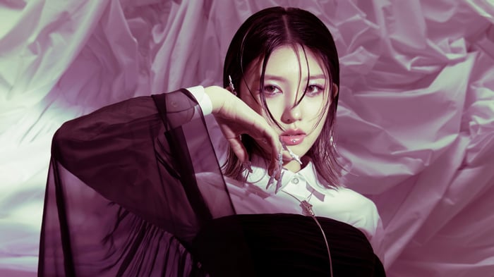 Gaeul from IVE posing in front of a draped background