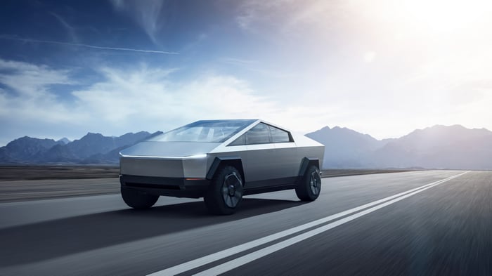 Tesla Cybertruck driving on a road with mountains