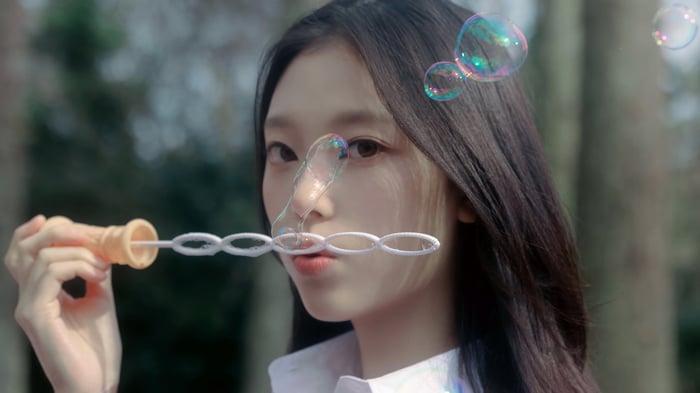 Haerin blowing bubbles with a bubble wand