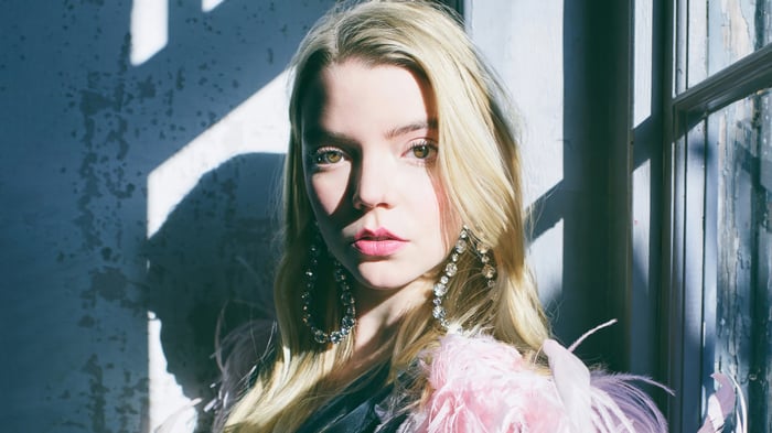 Anya Taylor-Joy in a pink feather boa and large earrings