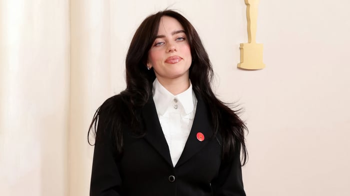 Billie Eilish in a black suit with an Oscar award