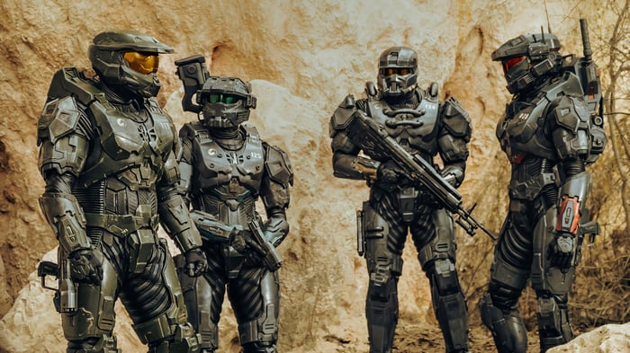 Four Spartans in Halo armor stand in a rocky area