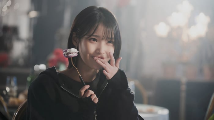 IU eating a macaron with a fork