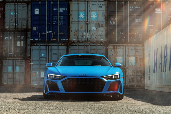 Blue Audi R8 parked in front of shipping containers