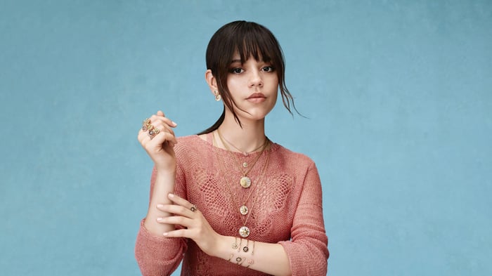 Jenna Ortega in a pink sweater with necklaces