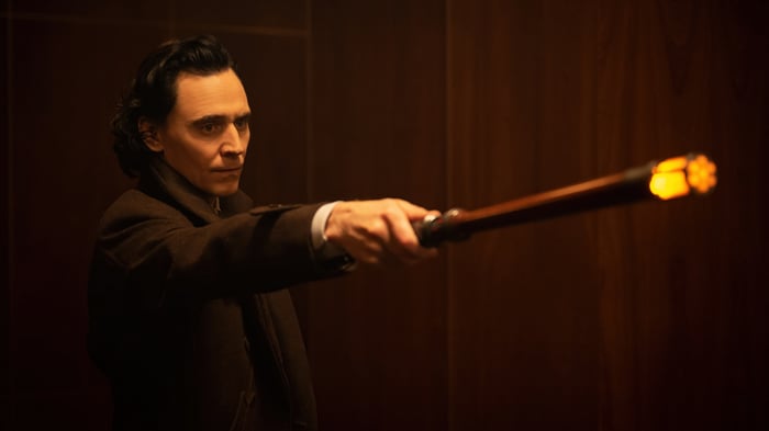 Tom Hiddleston as Loki holding a glowing staff