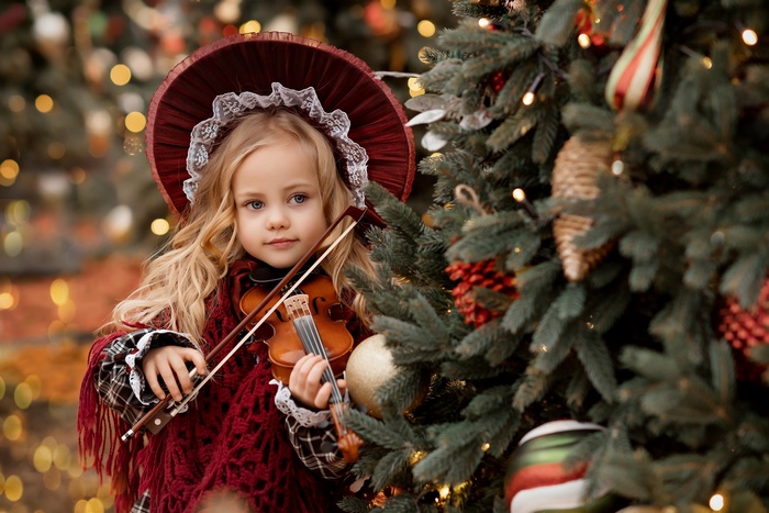 Girl in Hat Playing Violin Near Christmas Tree