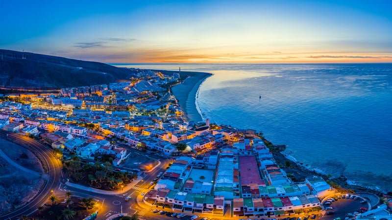 Coastal town at sunset with ocean and mountains