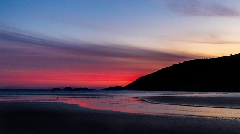 Sunset over a beach with a hill in Australia