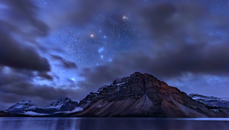Mountain range under starry sky reflected in lake