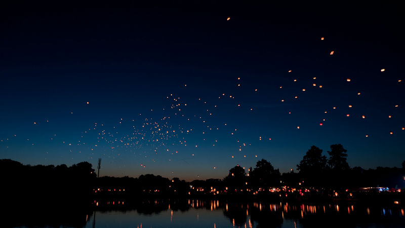 Sky lanterns float over a lake at night