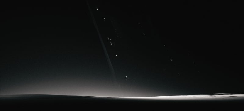 A lone figure stands on a dark planet with rings