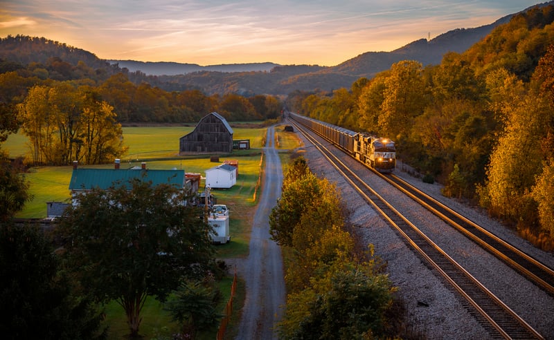 Train with headlights in a rural landscape at sunset