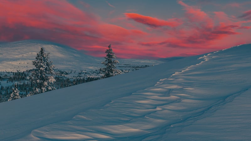 Snowy mountain landscape with sunset sky and tracks