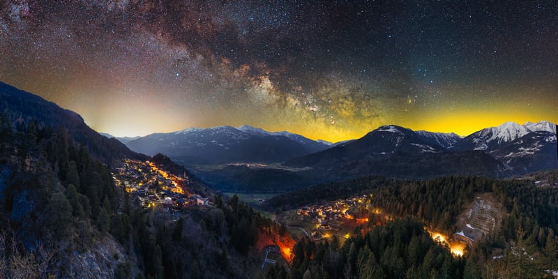 Village nestled in mountains under the Milky Way