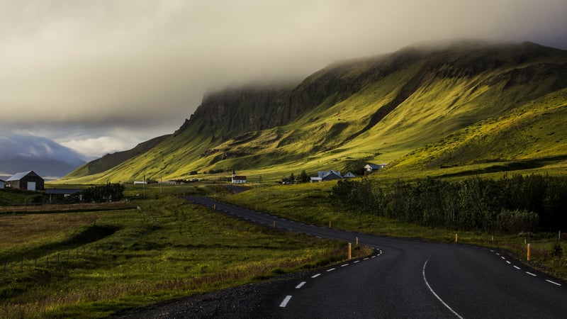 Winding road through a green valley with mountains