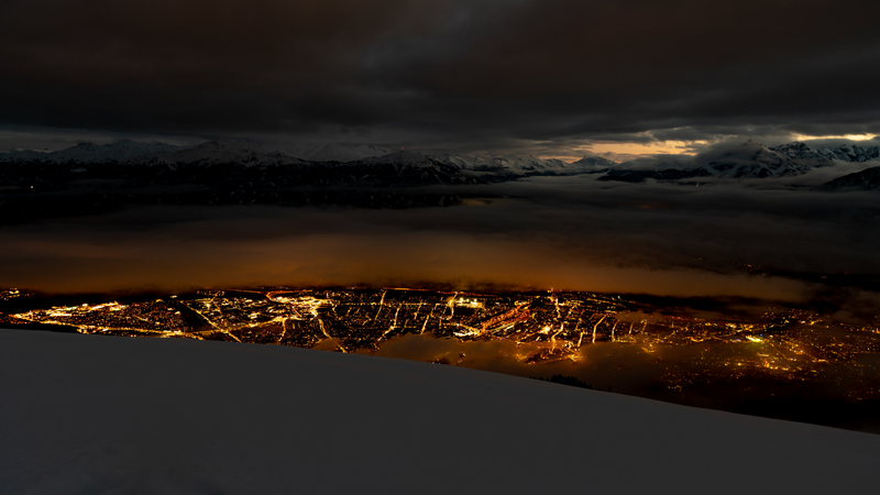 City lights at night with mountains and clouds