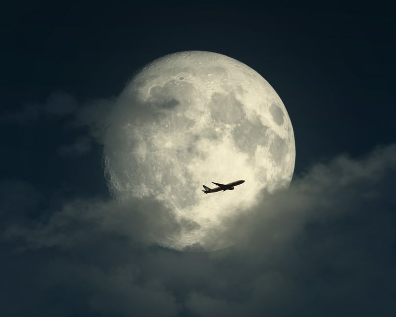 Airplane flying in front of the Moon
