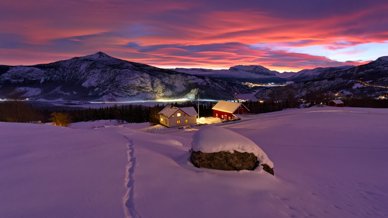 Snowy landscape with houses and mountains at sunset