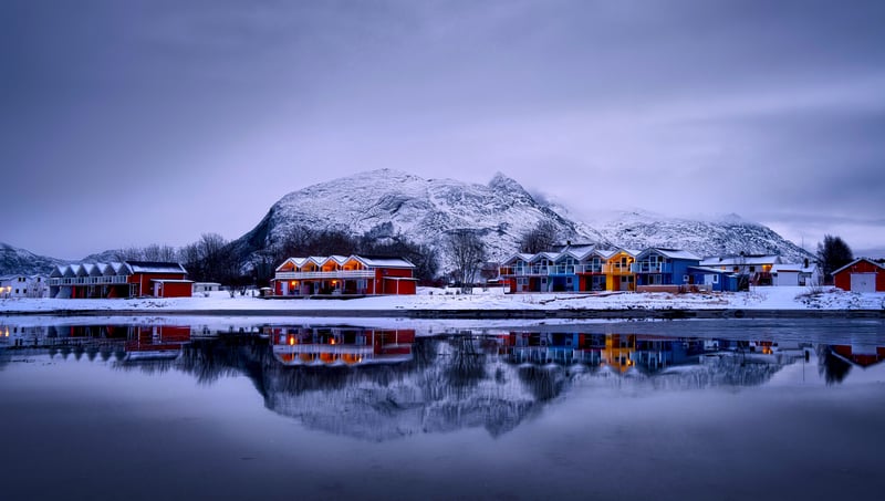 Snowy village with colorful houses reflected in water