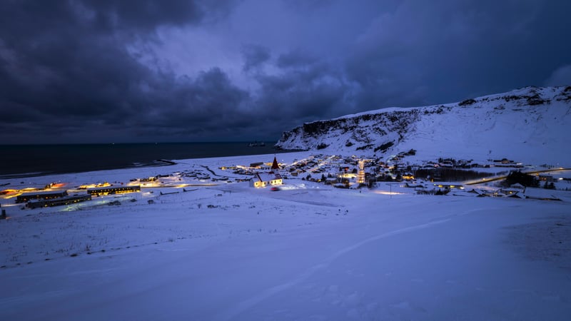 Snowy village at dusk with ocean and mountains