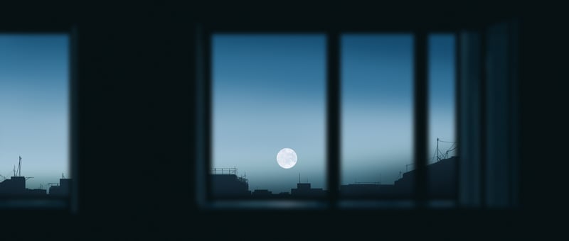 Full moon visible through a window overlooking a city
