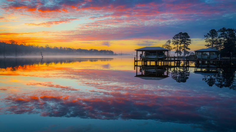 Boat docks on a lake at sunrise with colorful clouds