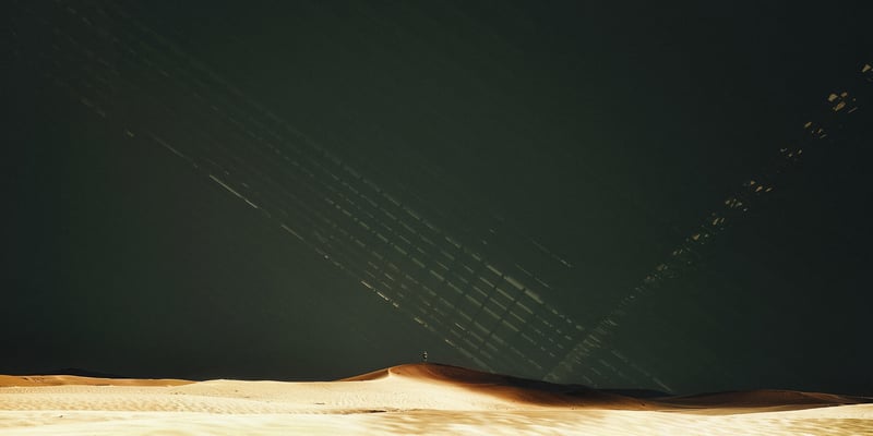 Man standing on a sand dune under abstract light patterns