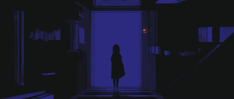 Silhouette of a woman standing in a blue lit doorway