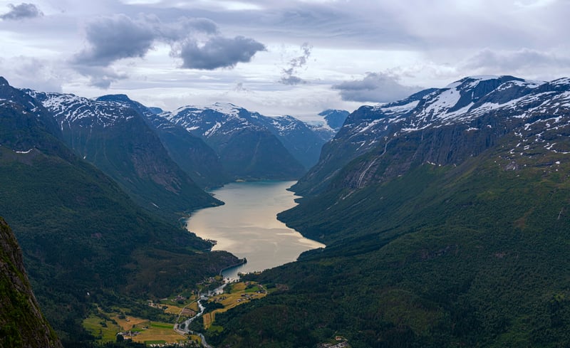 A wide valley with a lake and snow-capped mountains