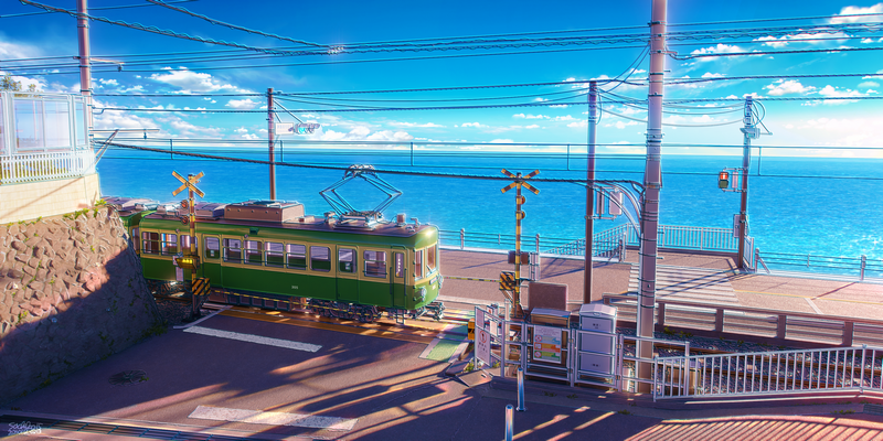 Green train by the sea with crossing signals