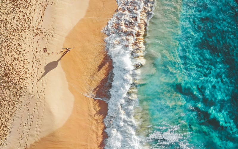 Aerial view of a beach with waves and footprints