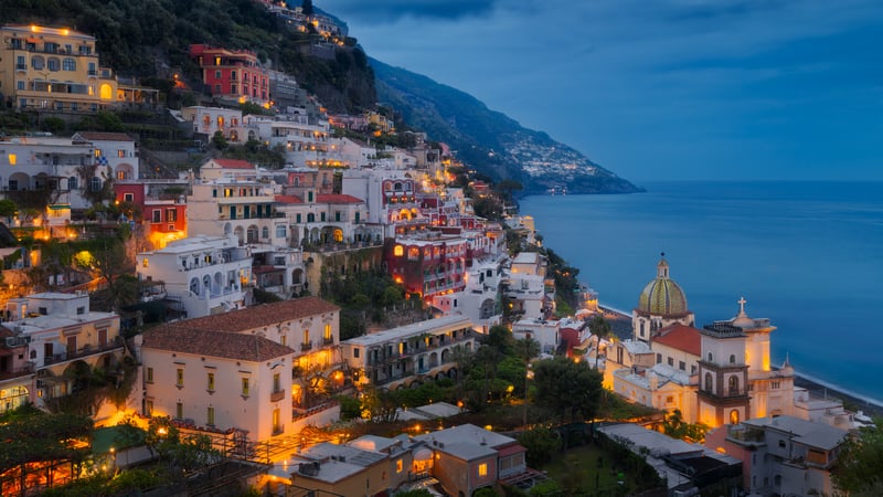 Positano village lights up at dusk by the sea