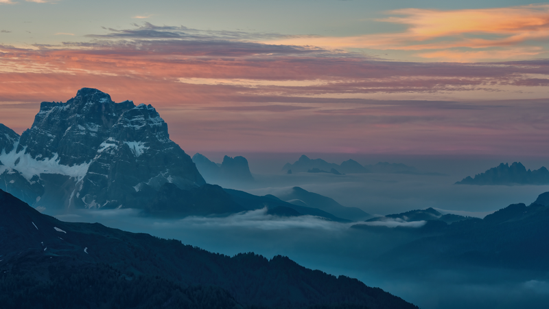 Mountain peaks emerge from mist at sunset