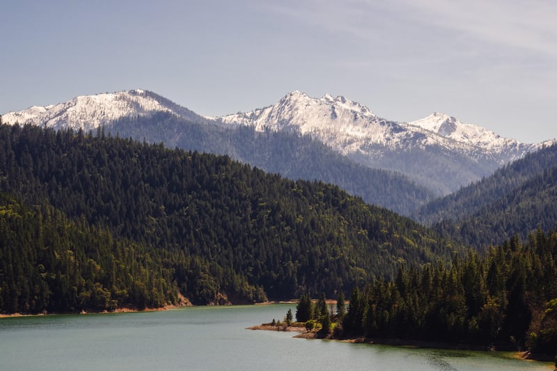 Snow-capped mountains overlook a forested lake in Oregon