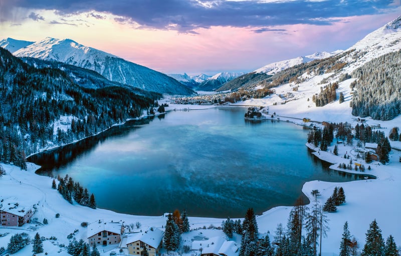 Snowy village by a lake surrounded by mountains